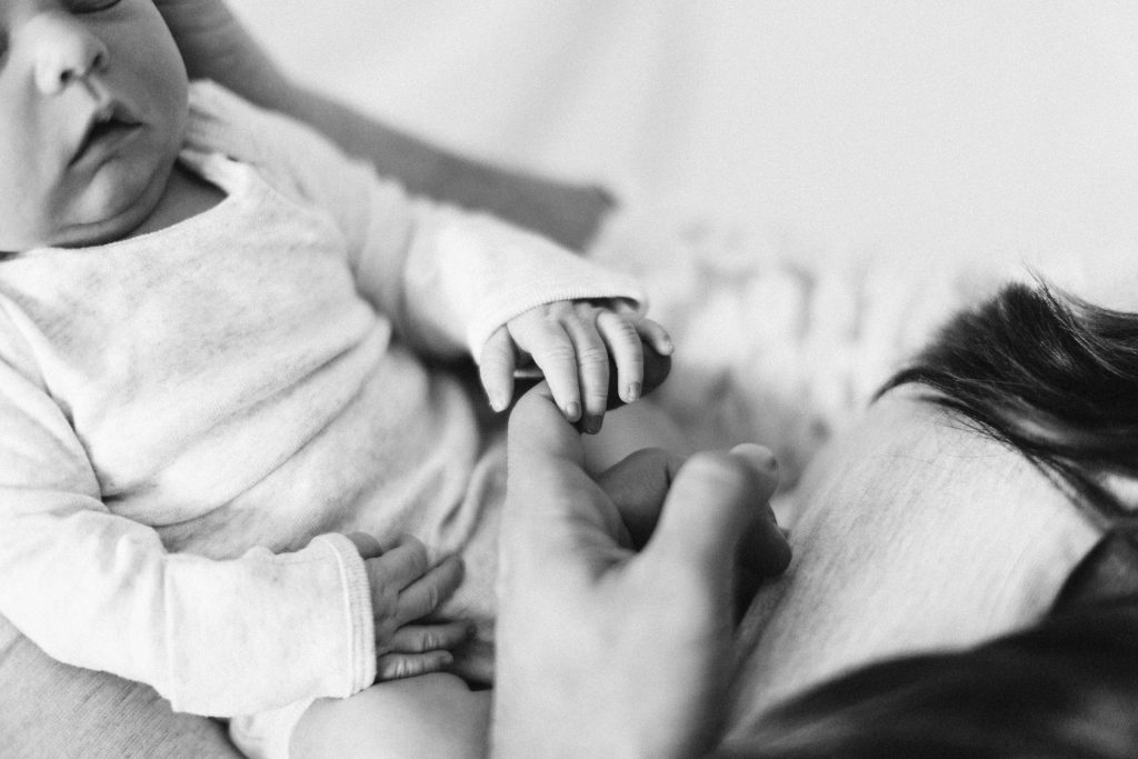 newborn holds mother's finger