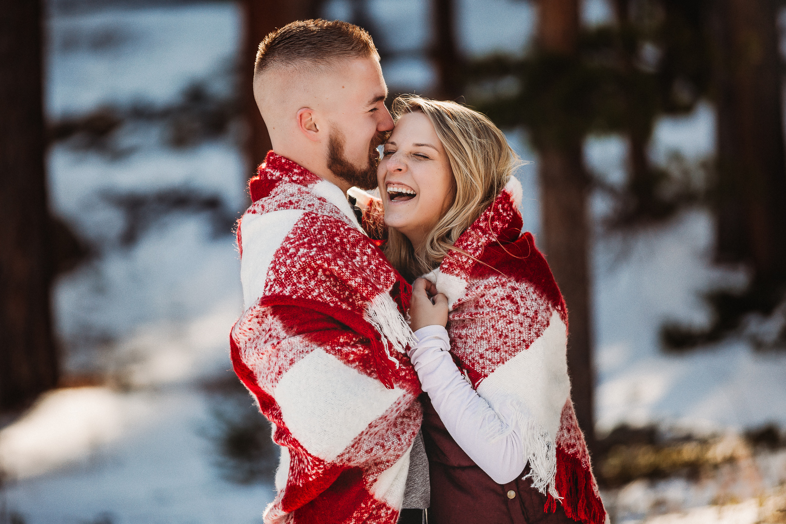 engaged couple laughs winter in Allenspark Colorado