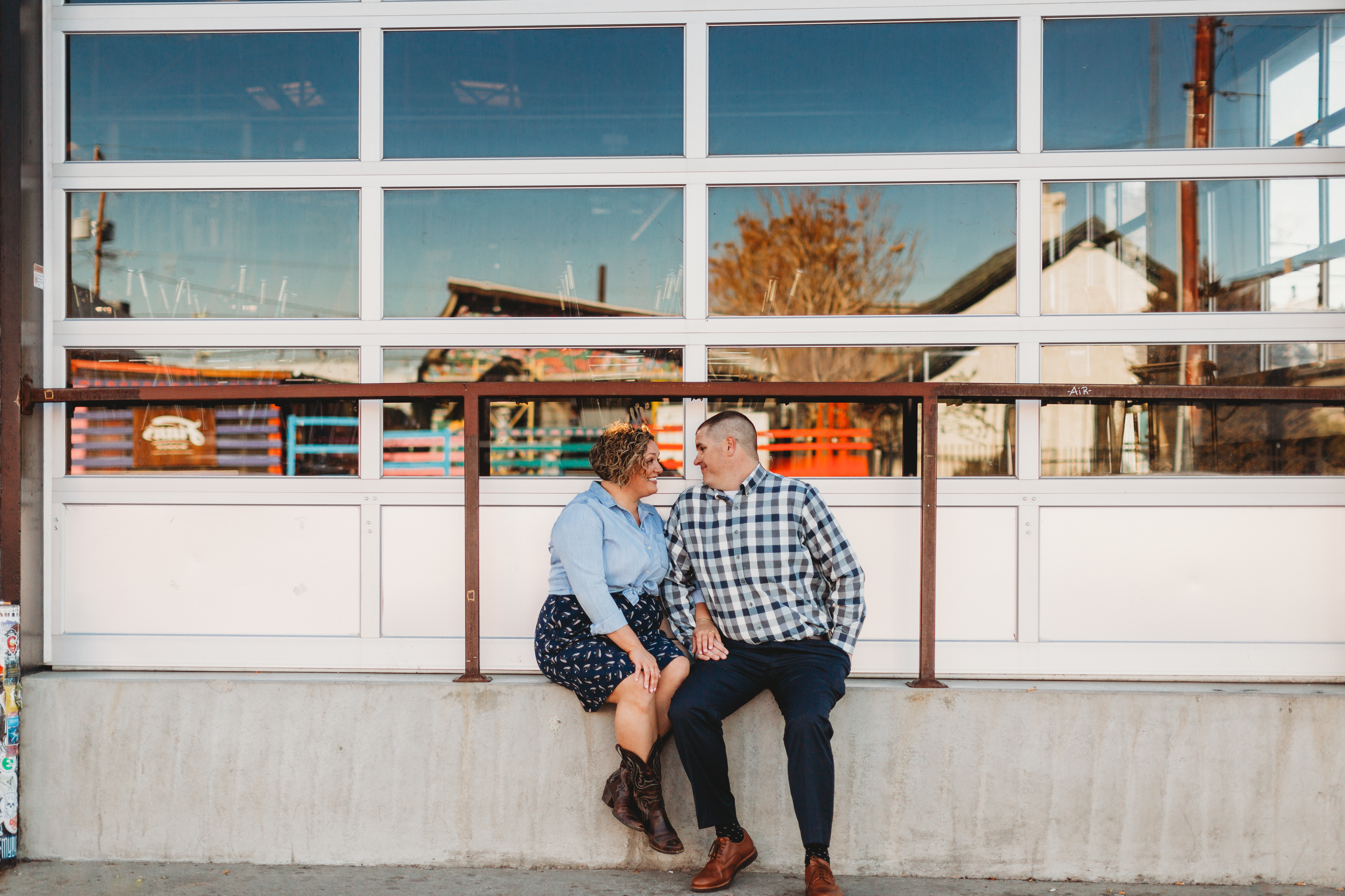 Engagement couple in front of reflected garage in RINO neighborhood