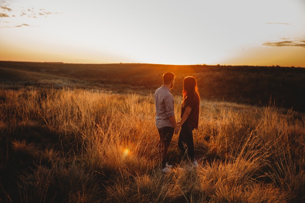 Engaged couple standing against mountain scenery during morning golden hour in Colorado