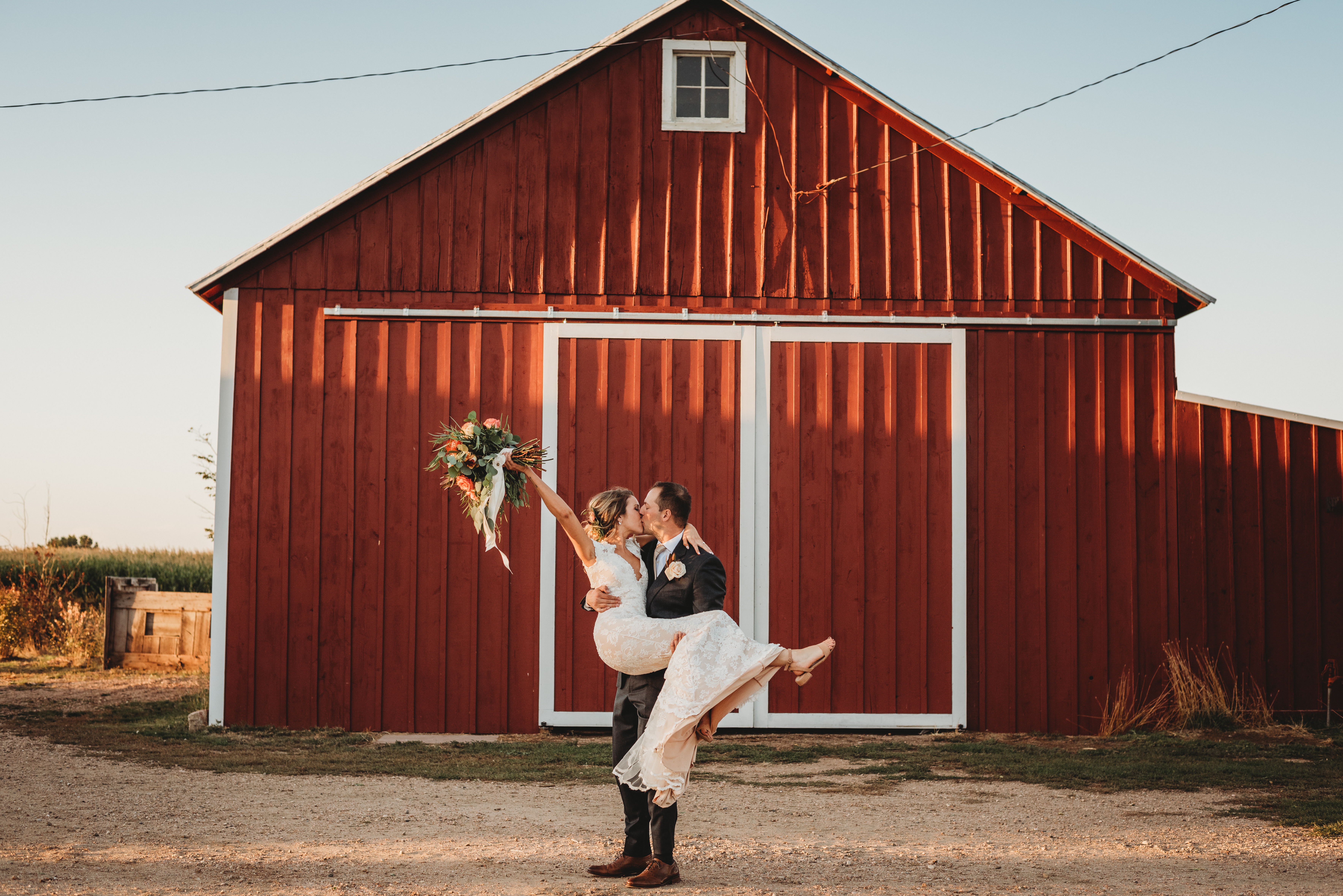 bride and groom kiss in front of the barn at Harmon Farms