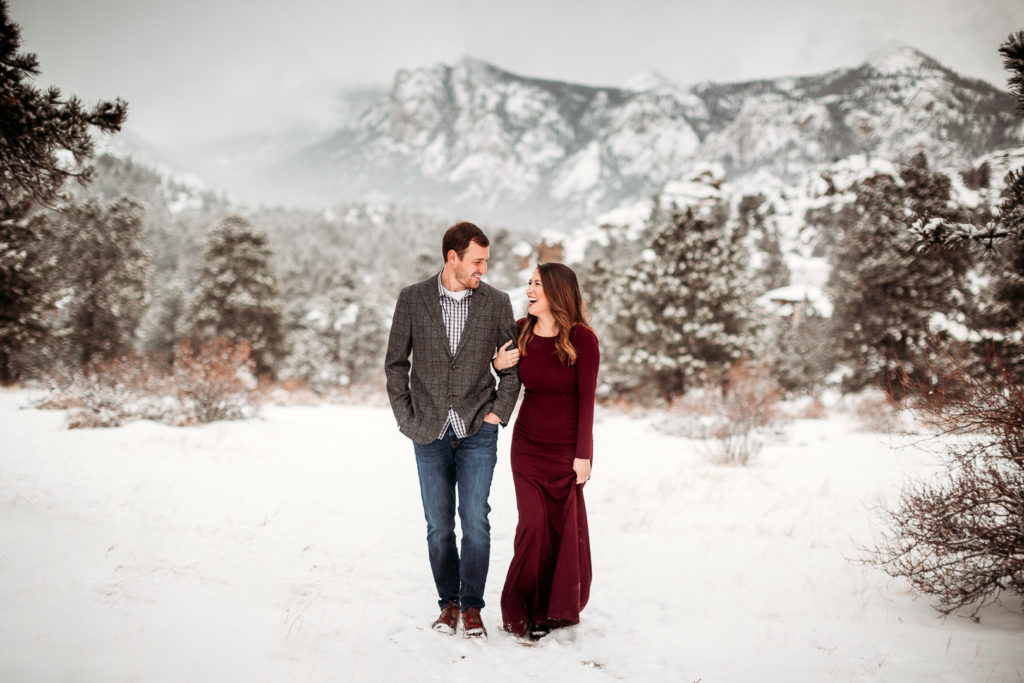 Couple walk in the snow during engagement photos in Estes Park
