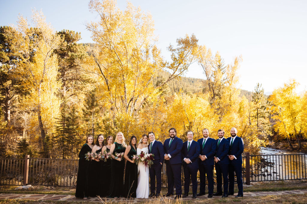 A bridal party poses for a photo at The Landing with the fall colors.